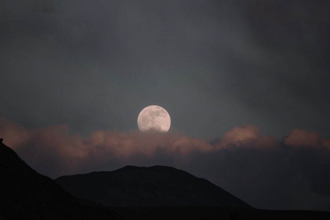 A full moon is seen over a mountain range