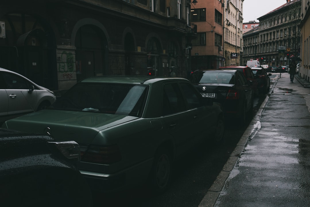 Cars parked on a narrow, wet city street.