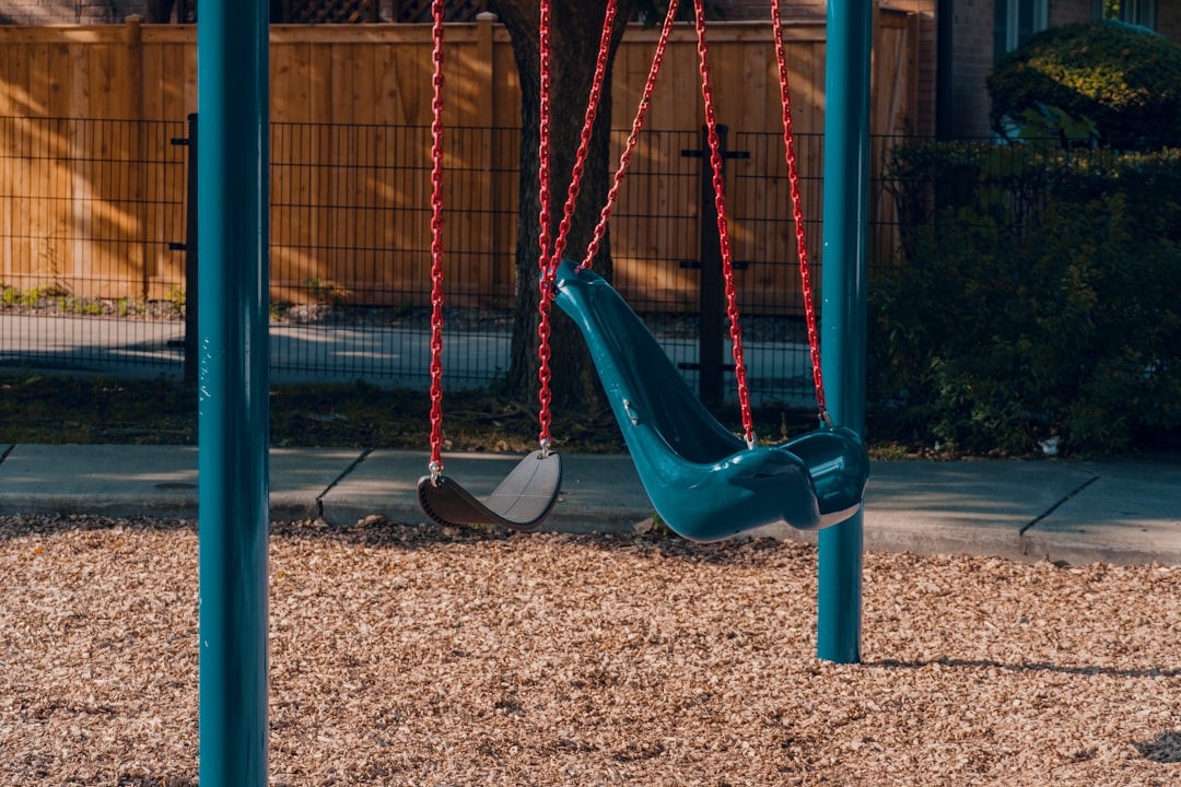 a blue swing set in a park with a red rope