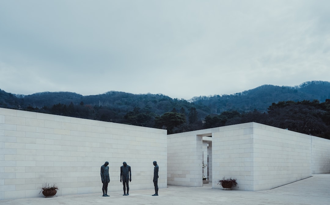 3 men standing on white concrete building during daytime